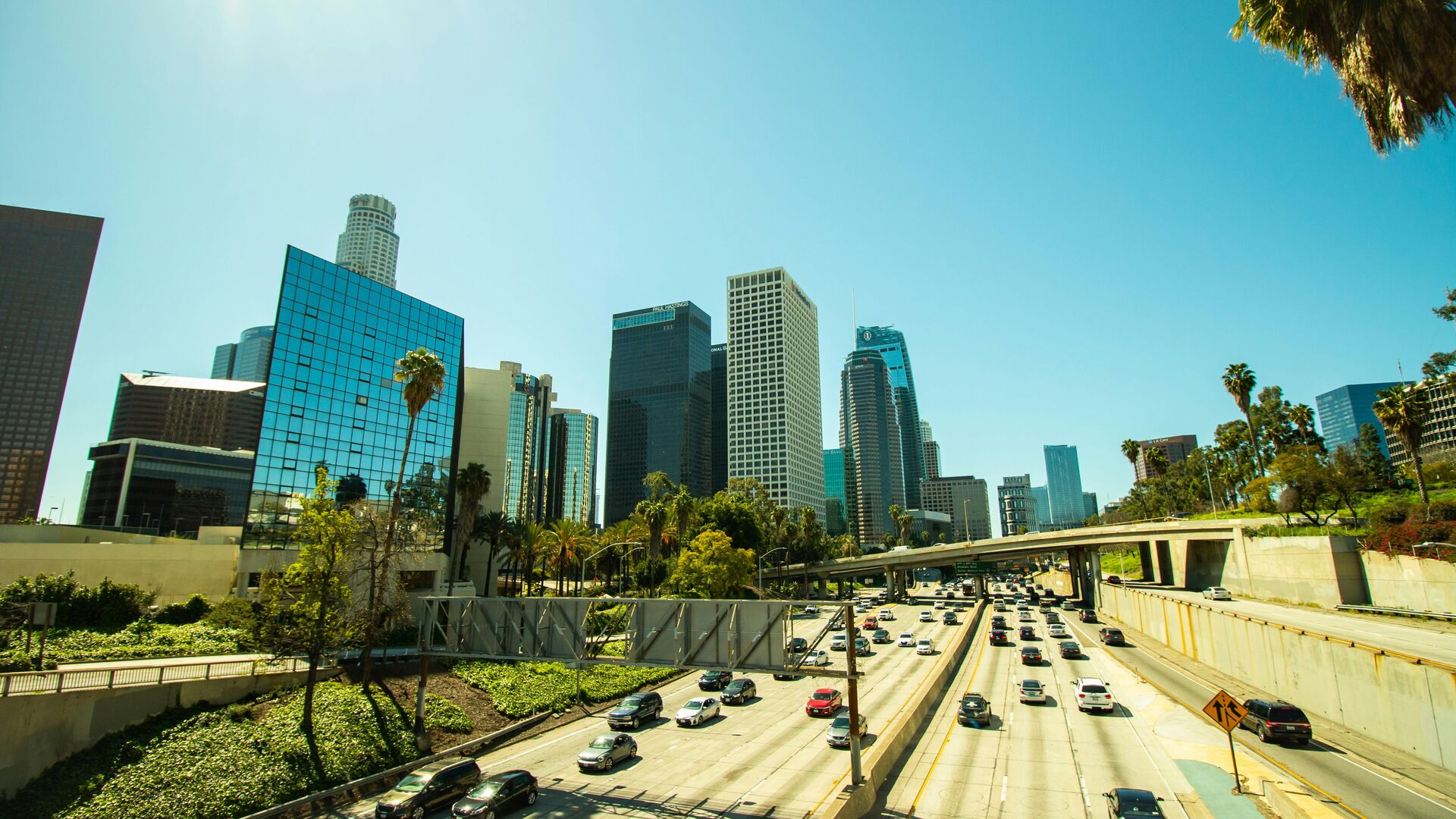 The downtown Los Angeles skyline above busy freeway traffic, representing the parking and access challenges of moving in the city